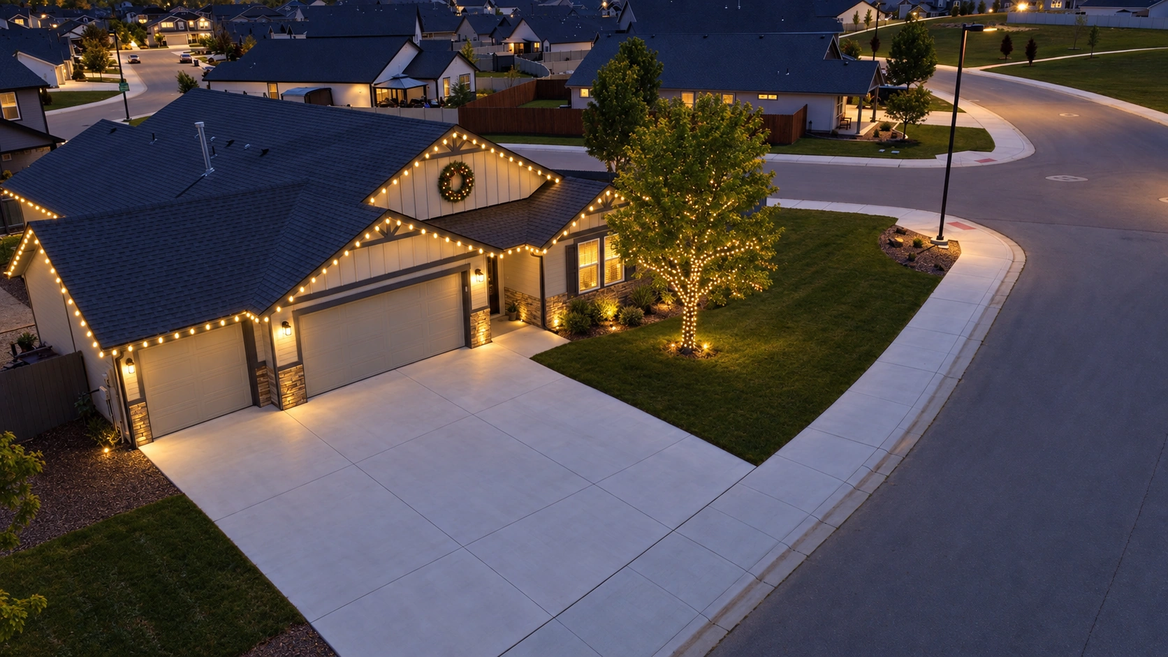 The finished Avondale home with warm white roofline lights, a lit wreath, and a wrapped ornamental tree at dusk